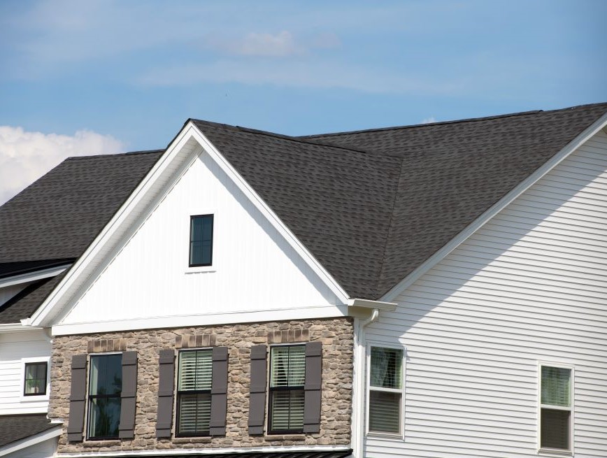 Stock image of residential home with brown rooftop and white siding